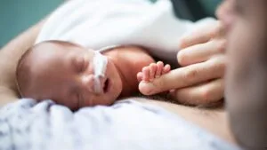 Πρόωρο μωρό με ρινικό καθετήρα που κρατάει το δάχτυλο ενός ενήλικα