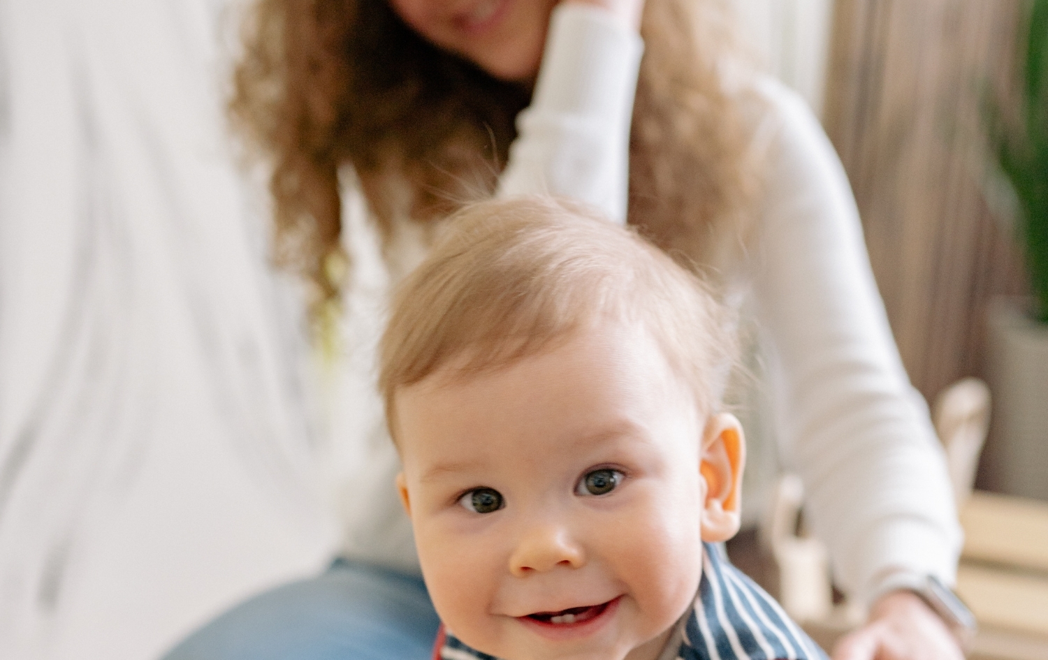 Μωρό χαμογελά ενώ αλληλεπιδρά με γονέα, ενισχύοντας τη γνωστική και κινητική ανάπτυξη.
